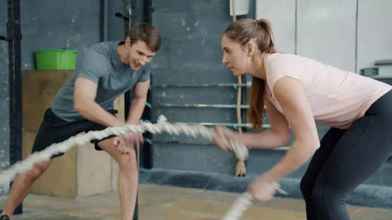 Two gym members performing battle rope exercises during a functional training session