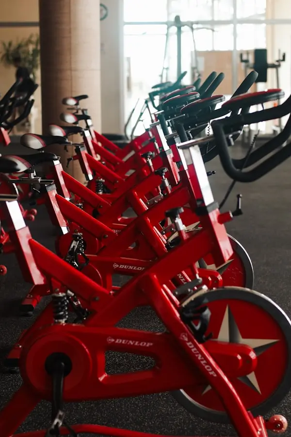 Row of red stationary spin bikes arranged inside a modern gym training area
