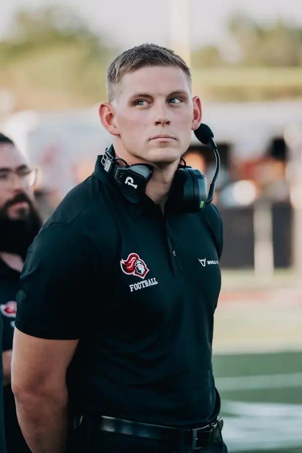 Coach standing on a sports field wearing a headset during an outdoor training session
